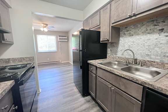 A kitchen with a black fridge and a marble countertop.