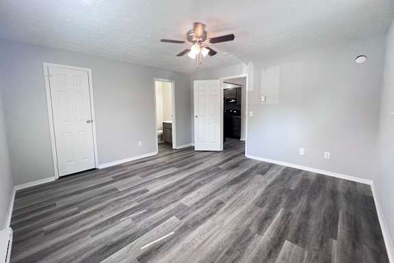 A room with a ceiling fan and wood flooring.