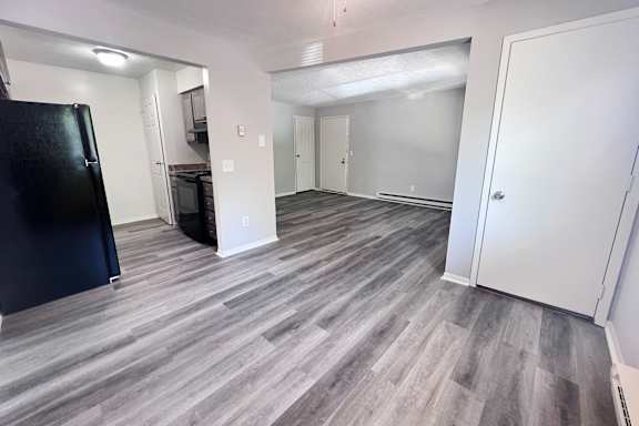 A kitchen area with a black fridge and a grey floor.