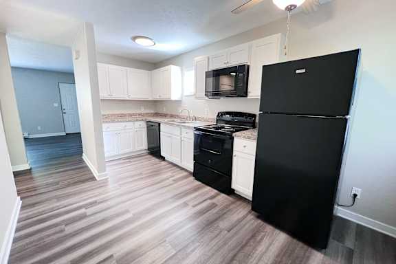 A kitchen with black appliances and white cabinets.