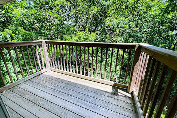A wooden deck with a railing overlooking a green forest.