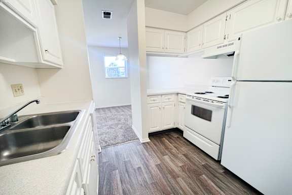 A white kitchen with a sink and a refrigerator.
