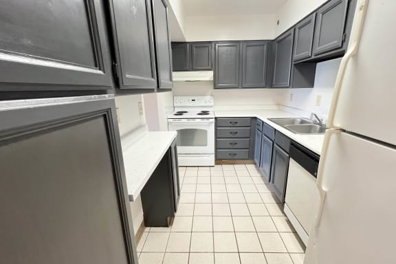 an empty kitchen with black cabinets and white appliances