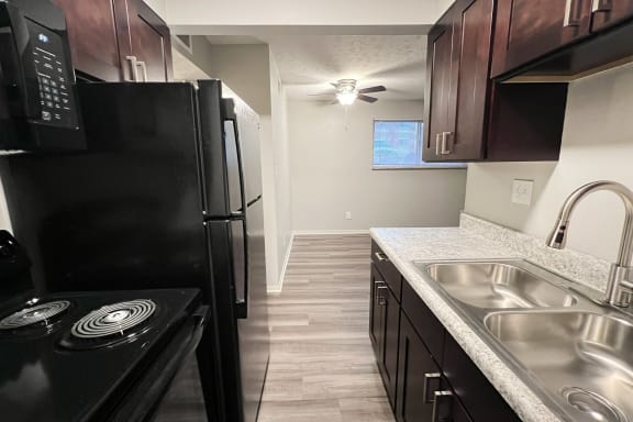 an empty kitchen with black appliances and a stainless steel sink at Crown Crossing Apartments, Amelia, OH
