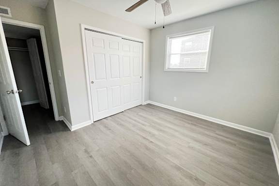 an empty living room with wood floors and a white door