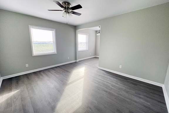 an empty living room with hardwood floors and a ceiling fan