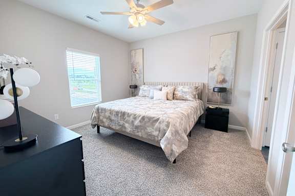 Carpeted bedroom with neutral walls and ceiling fan at The Meridian on 32 Apartments, Batavia, OH