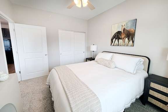 Furnished bedroom with white bedding and wall art at The Meridian on 32 Apartments, Batavia, OH 45103