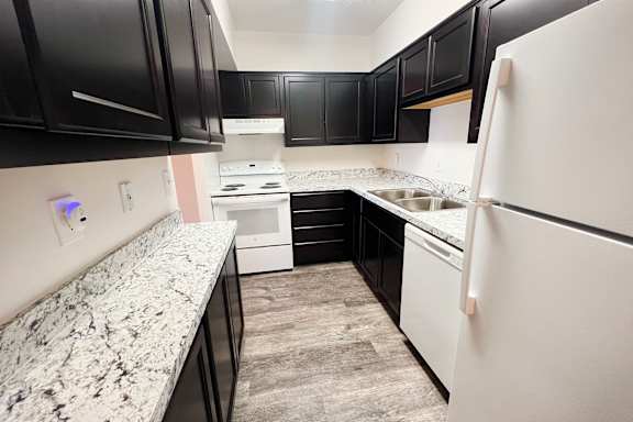A kitchen with black cabinets and a white refrigerator at Indian Lookout Apartments, Cincinnati
