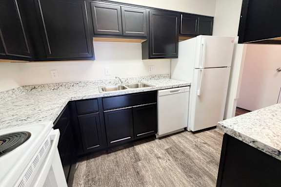 an empty kitchen with white appliances and black cabinets