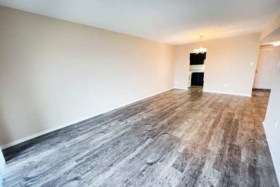 an empty living room with vinyl flooring and white walls