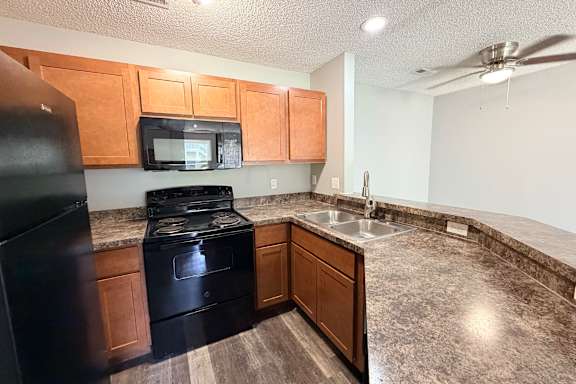 A kitchen with black appliances and wooden cabinets.