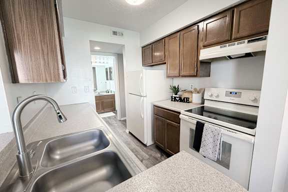 A kitchen with a stainless steel sink and white appliances.