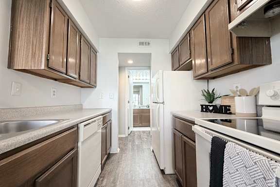 A kitchen with brown cabinets and a white fridge.