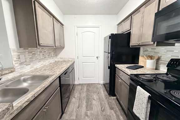 A kitchen with black appliances and wooden cabinets.
