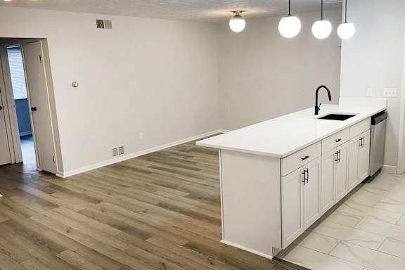 A kitchen with white cabinets and a wooden floor.