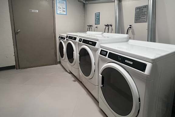 A row of white washing machines in a laundromat.