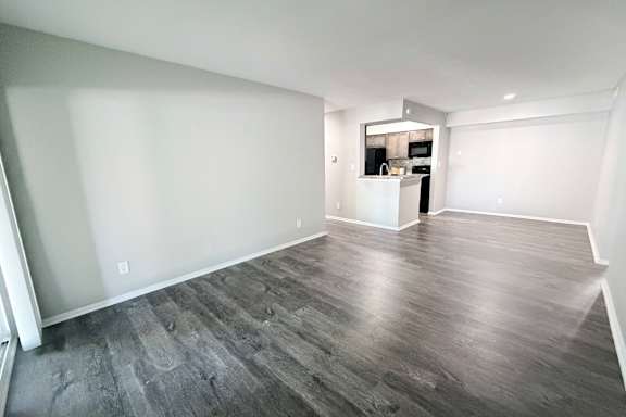 A spacious room with wooden flooring and white walls.