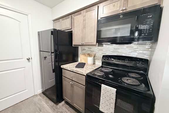 A black stove and refrigerator in a kitchen.