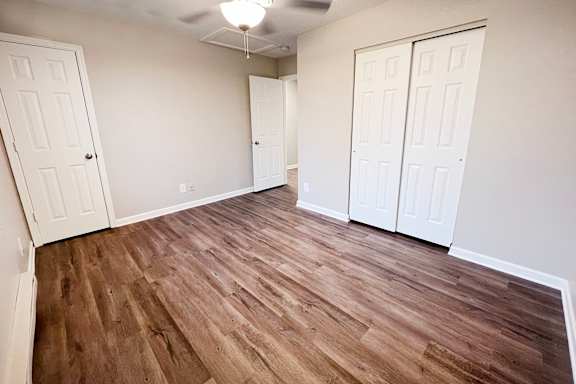 A room with wood flooring and two white doors.
