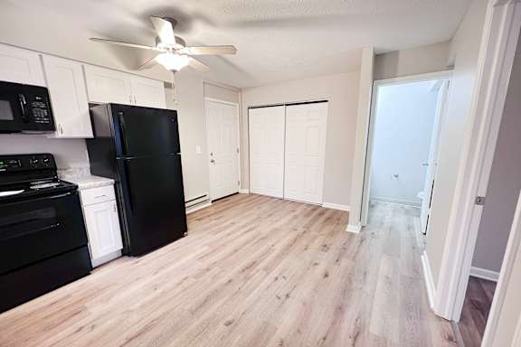 A kitchen with black appliances and wooden floors.