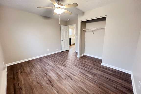 A room with a ceiling fan and wooden flooring.