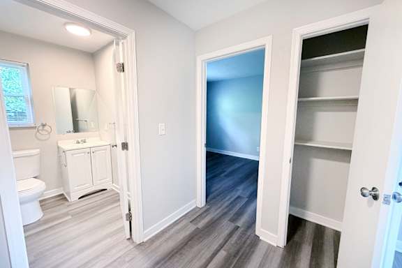 A bathroom with a toilet, sink, and a door leading to another room.