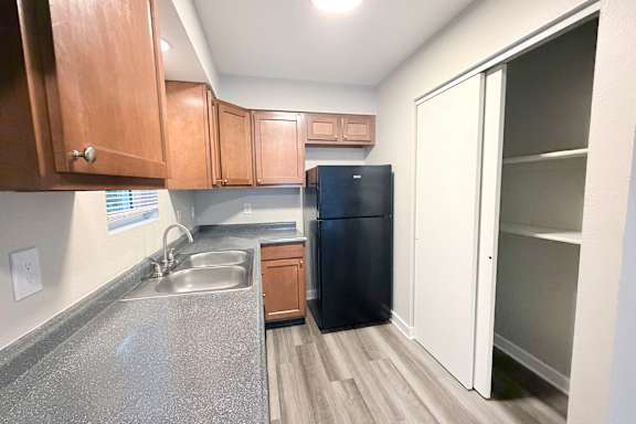 A kitchen with a black fridge and wooden cabinets.