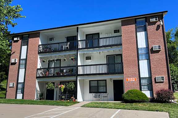 Apartment building number 1132 with a balcony and a small garden.