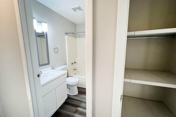 A white bathroom with a toilet, sink, and a walk-in shower.