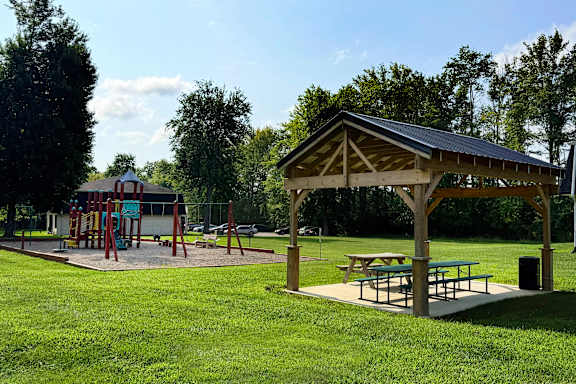A playground with a swing set and picnic tables.