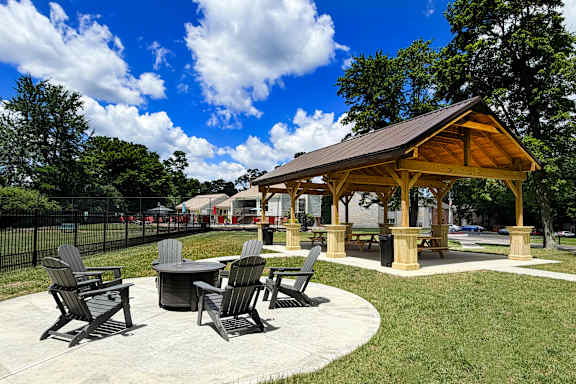 A pavilion with a table and chairs is surrounded by a grassy area.