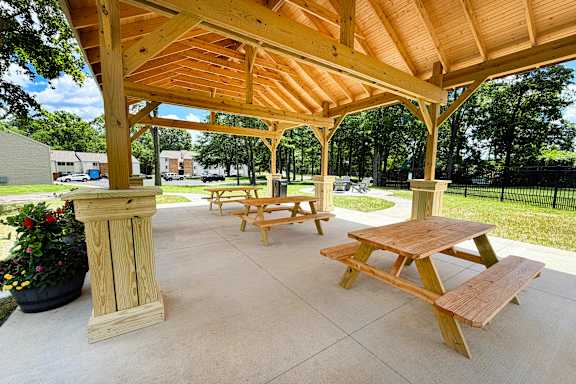 A wooden pavilion with benches and a pillar.