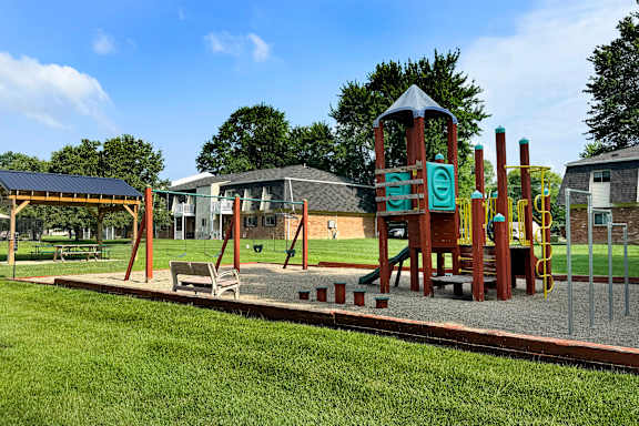 A playground with a wooden swing set and a green slide.