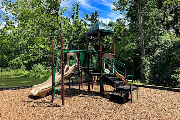 A playground with a green slide and a yellow slide.