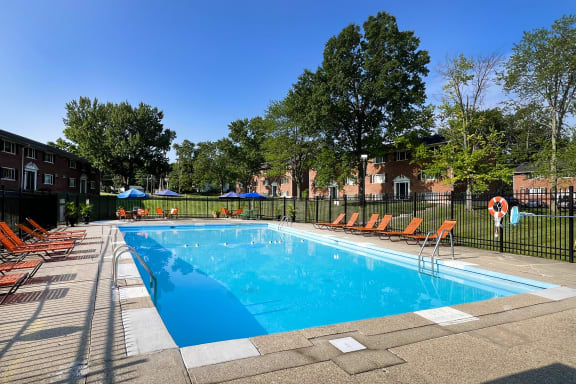 a swimming pool with chairs around it in front of a building at Sharondale Woods Apartments, Cincinnati