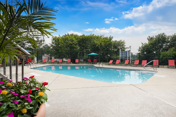 a swimming pool with red lounge chairs and trees in the background  at Hunter's Creek Apartments, Ohio, 45242