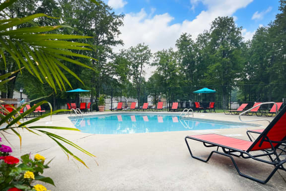 a swimming pool with red chaise lounge chairs and umbrellas  at Hunter's Creek Apartments, Cincinnati, OH