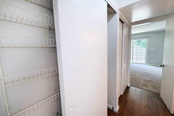 A white refrigerator with empty shelves in a room with a door leading to a hallway.
