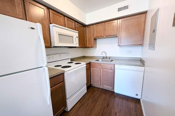 A kitchen with white appliances and wooden cabinets.