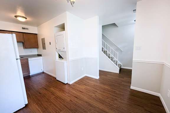 A kitchen with white appliances and wooden floors.