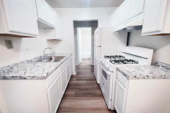 A kitchen with white cabinets and granite countertops.