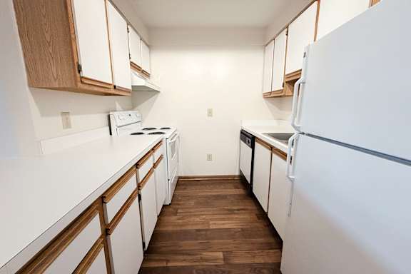 A kitchen with white appliances and wooden cabinets.