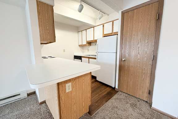 A kitchen with a white counter and a white fridge.