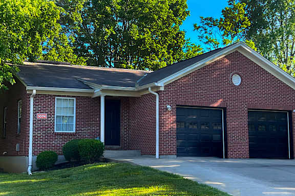 A red brick house with a black garage door.