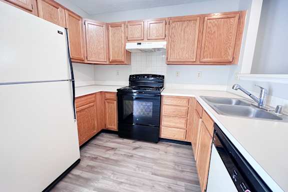 A kitchen with a white fridge and black oven.