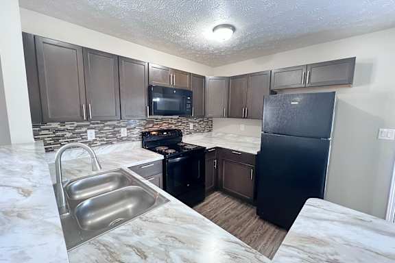 A kitchen with a black fridge and a black stove.