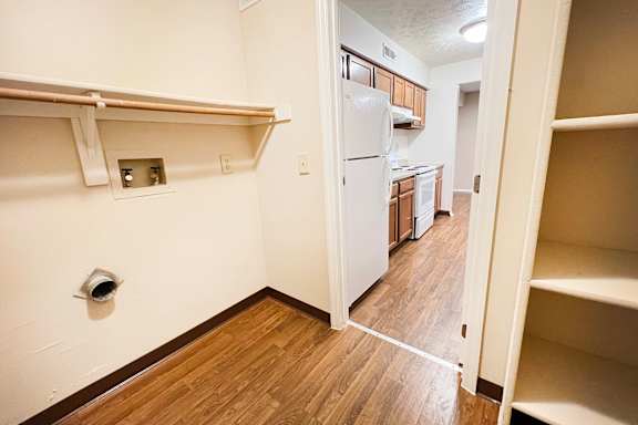 a view of a kitchen and a hallway with wood flooring and a white refrigerator