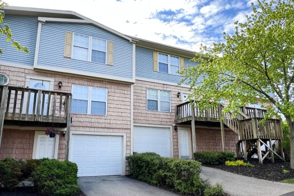 a view of a two story apartment building with two garages and a balcony