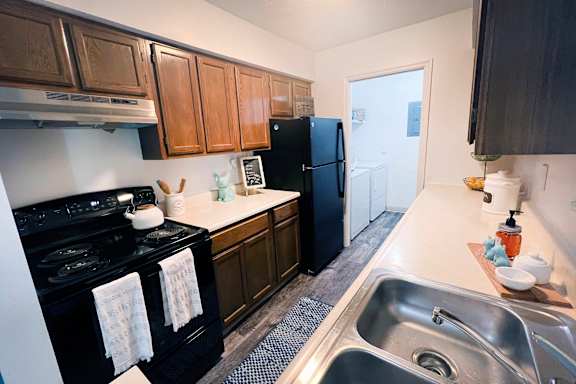 A kitchen with black appliances and wooden cabinets.